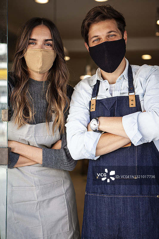 年轻男女戴着防护口罩站在健康食品市场入口处的肖像图片素材