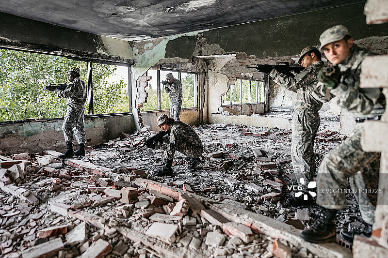 军事突击小队在废弃建筑的走廊里盯梢图片素材