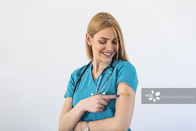 年轻女医生，在接种冠状病毒疫苗后，手臂上贴绷带。急救。医疗、制药和保健理念。图片素材