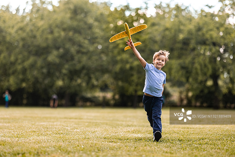 男孩正在公园里玩飞机玩具图片素材