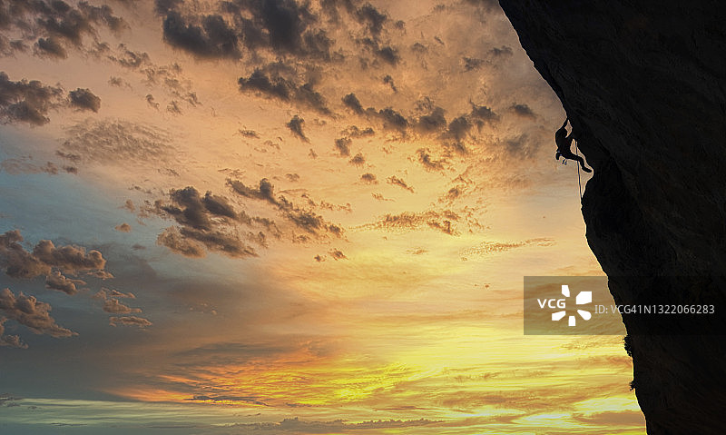 日落时分，一名登山者站在岩壁上图片素材