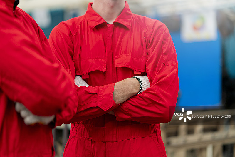 身着红色安全制服的专业工程师形象，自信地站在工厂背景下图片素材