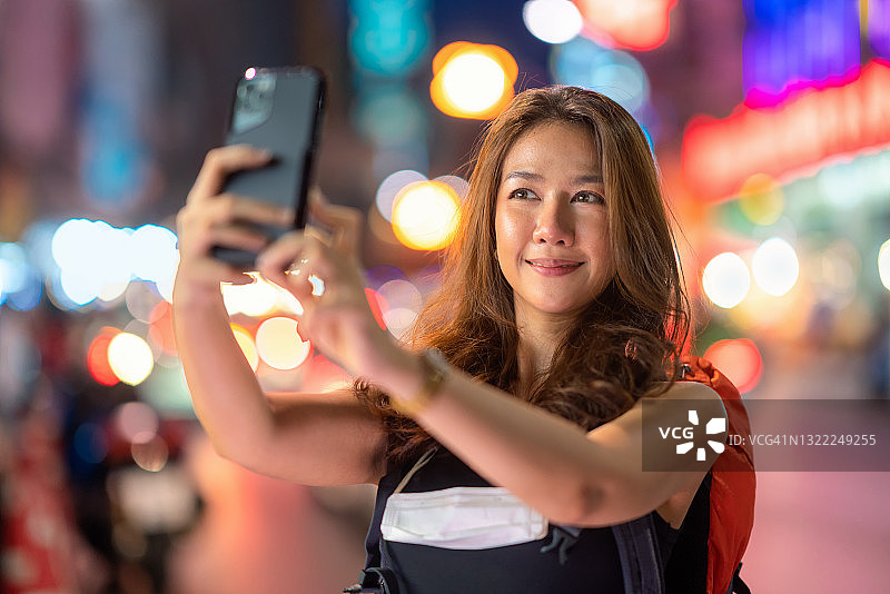 这个年轻漂亮的女人自拍自己展示她的朋友的社交网络，并在泰国曼谷的唐人街推广自己。图片素材