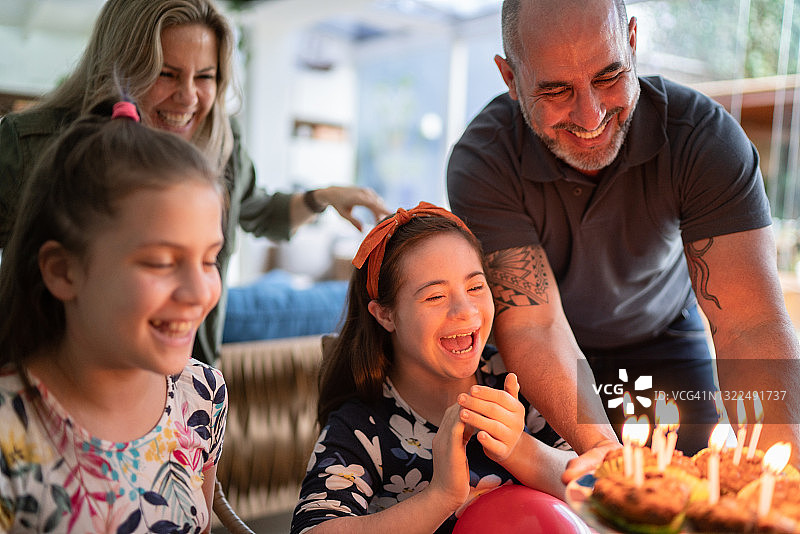 一个家庭在家庆祝女儿的生日——包括一个特殊需要的女孩图片素材