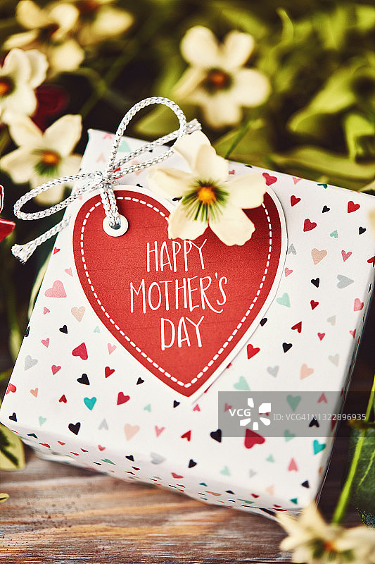 母亲节的礼物与手工礼品标签在鲜花和树叶图片素材