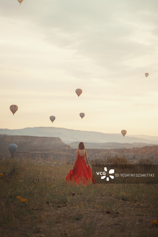 卡帕多西亚，身着红裙的女子，日出和热气球。图片素材