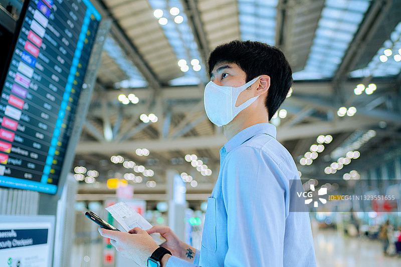 一名年轻的亚洲男子在机场用智能手机检查登机牌图片素材