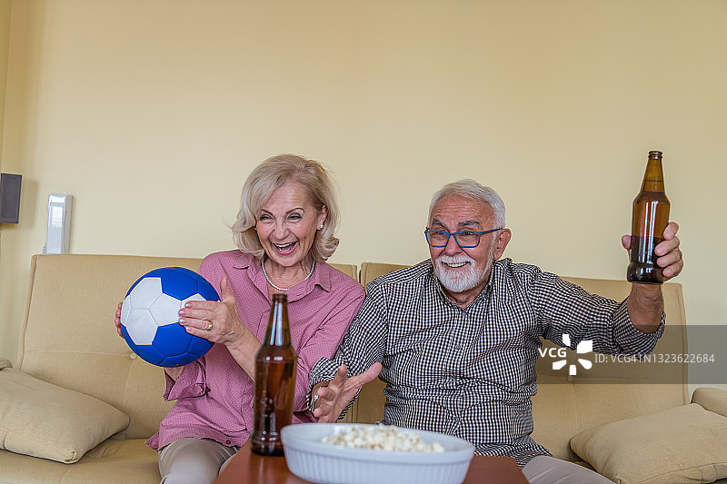 一对快乐的老夫妇在家看足球比赛。图片素材