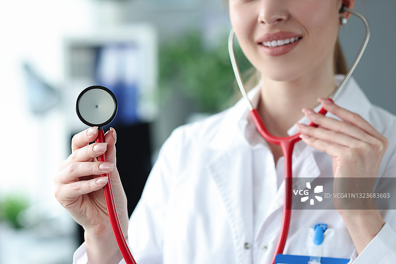 年轻女医生手持红色听诊器在诊所特写图片素材