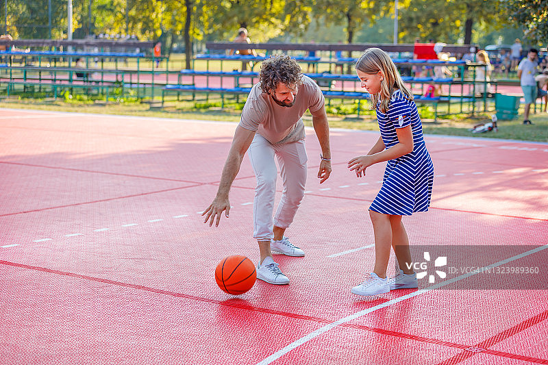 一个快乐的父亲和女儿正在享受户外和打篮球。图片素材