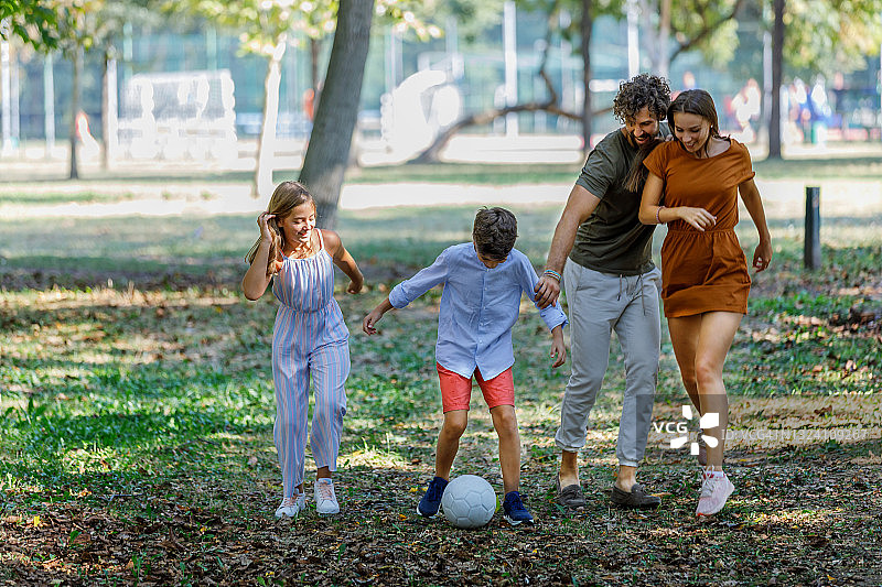快乐小家庭在大自然中玩足球。图片素材