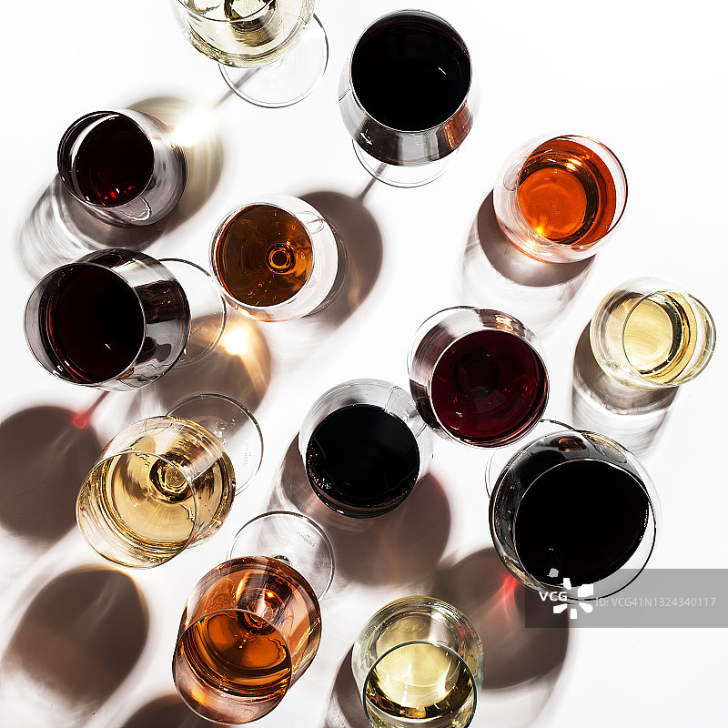 红色，玫瑰和白葡萄酒的玻璃杯在白色的背景，俯视图。酒吧，商店，酿酒厂，品酒概念。强光和刺眼的阴影图片素材