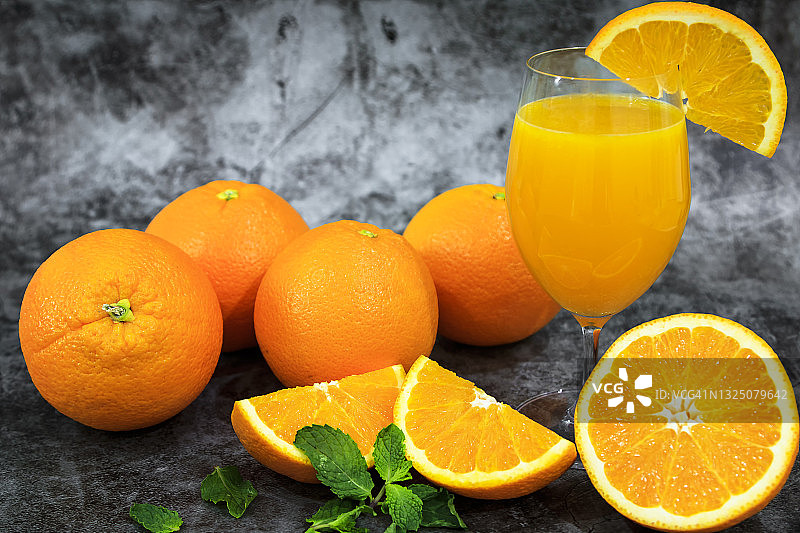 杯中的橙汁，深色背景为鲜橙图片素材