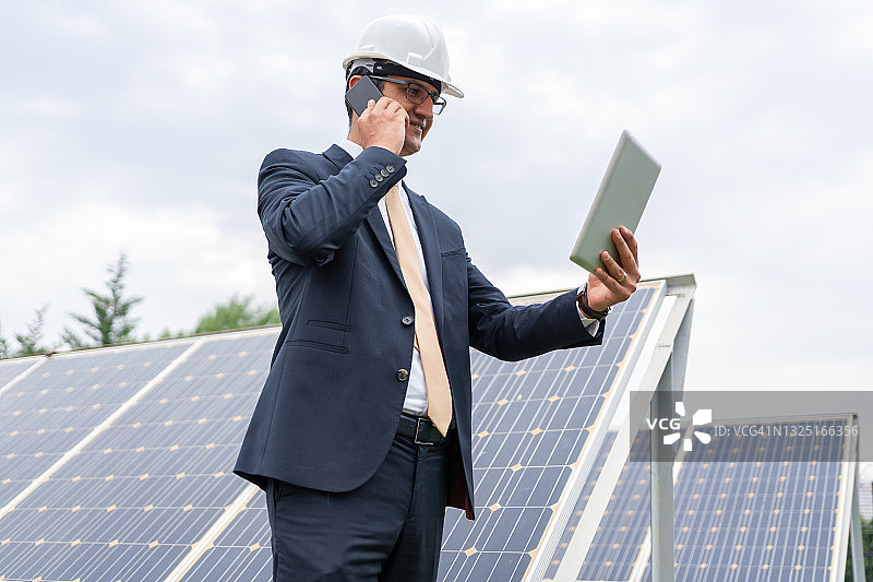 一男经理工程师İn安全帽检查平板太阳能电站太阳能电池板系统的操作图片素材