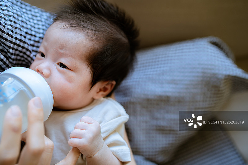 年轻的母亲正在给怀里刚出生的小婴儿喂奶。图片素材