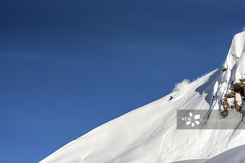 极速滑雪者从阳光明媚的山脊上下来图片素材