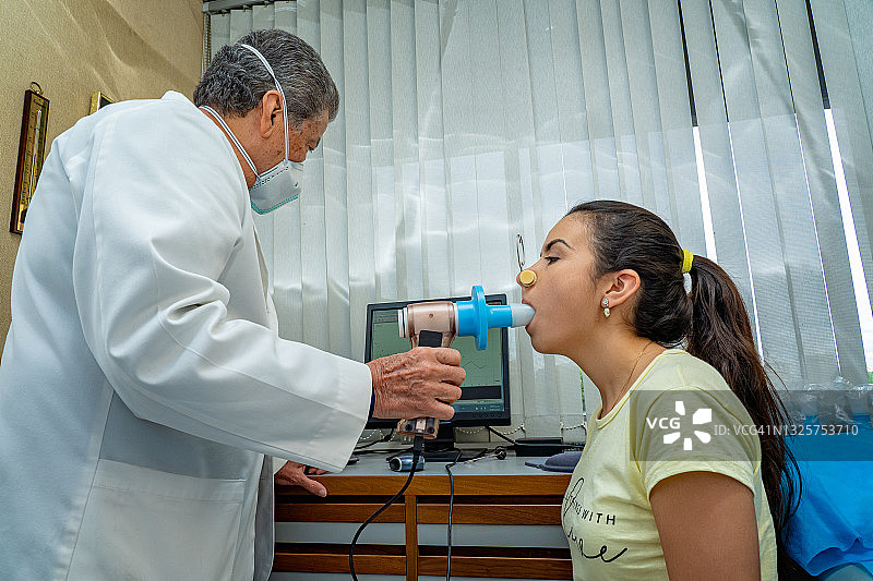 西班牙裔年轻女子在医生办公室进行肺功能测试和肺量测定图片素材