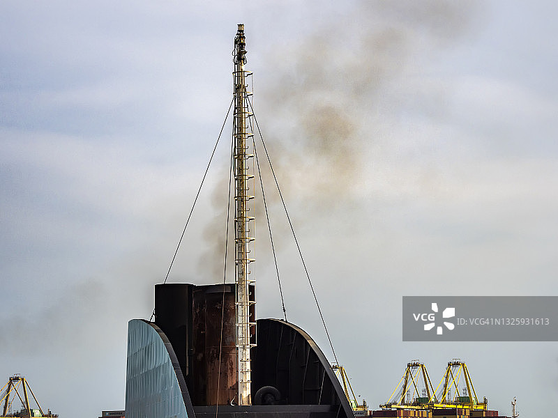 港口里一艘大型货船的烟囱产生的烟雾污染。图片素材
