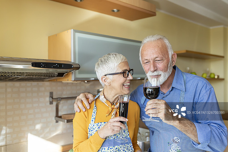 一对老夫妇在家里享受红酒。爱永不老去。图片素材