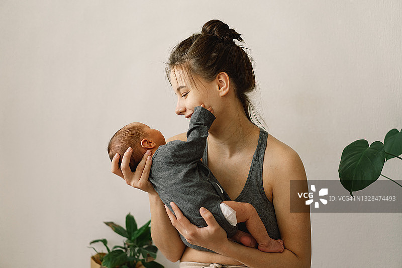 母亲节概念。母亲在家里抱着刚出生的儿子。宝宝和妈妈快乐。图片素材