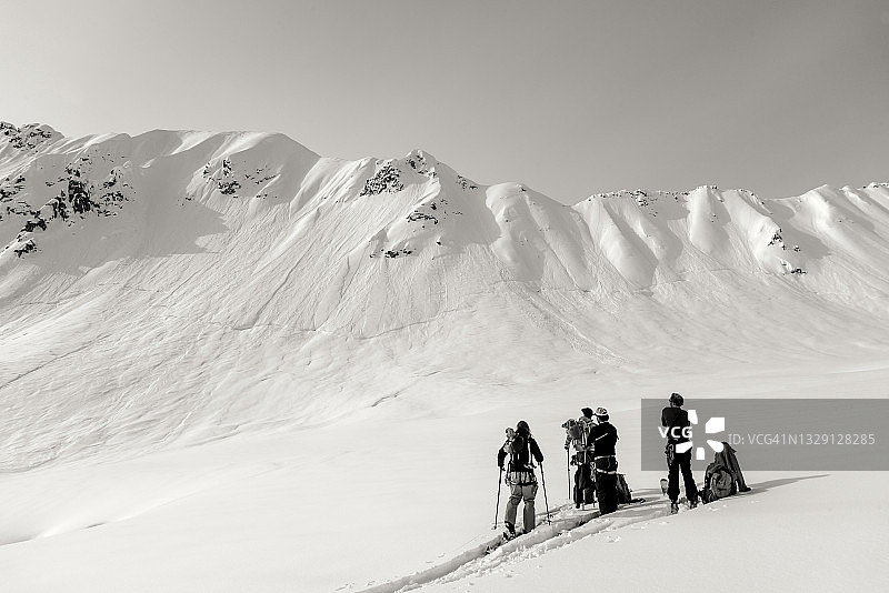 偏远地区的滑雪者在漫长的攀登前在雪坡上放松图片素材