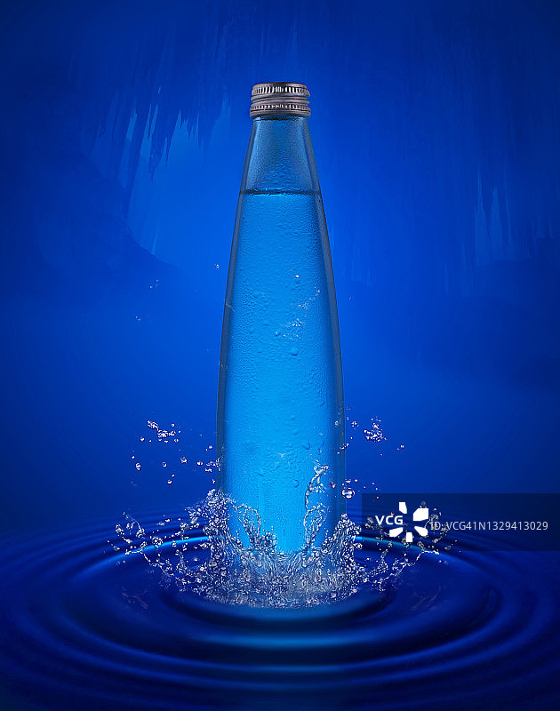 在蓝色背景下，一个装有水晶般清澈的水的玻璃瓶在水中溅起水花。特写镜头图片素材