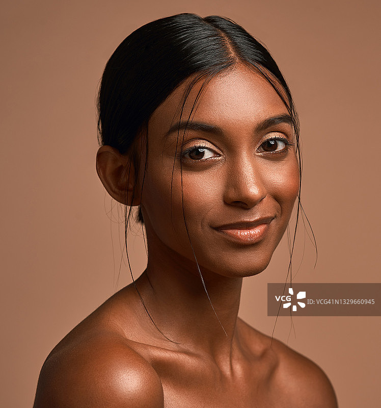 一个美丽的年轻女子的肖像在一个棕色的背景下摆姿势图片素材