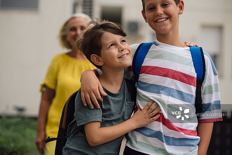 两个上小学的男孩抱在一起，准备上学。图片素材