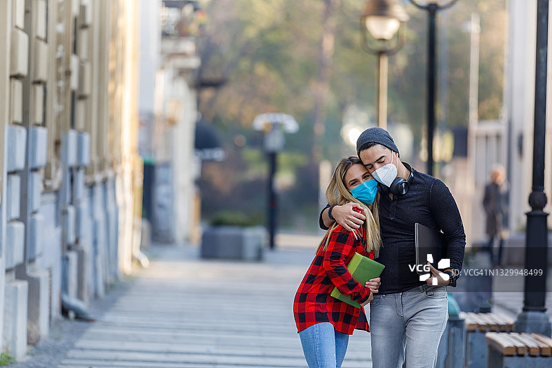 这是一对快乐的相爱的年轻夫妇的肖像，他们在城市的街道上接吻，在疫情期间交换可爱的话语。图片素材