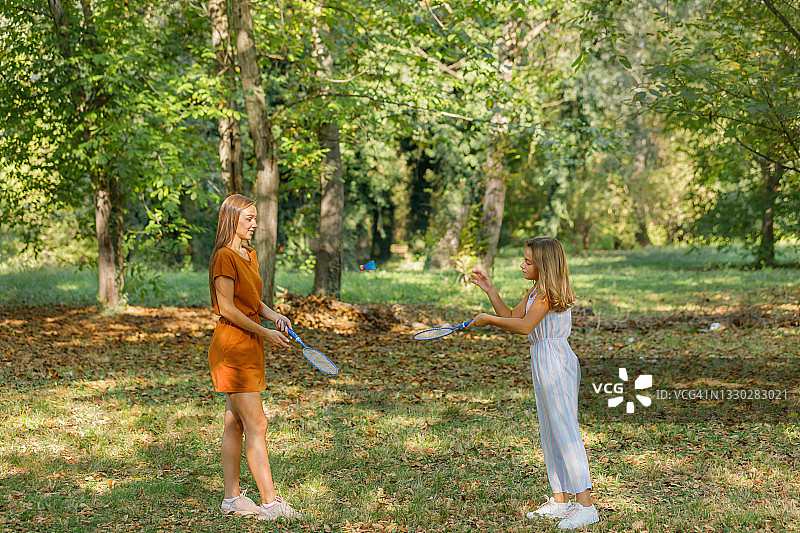 快乐的妈妈和女儿在享受大自然和打羽毛球。图片素材
