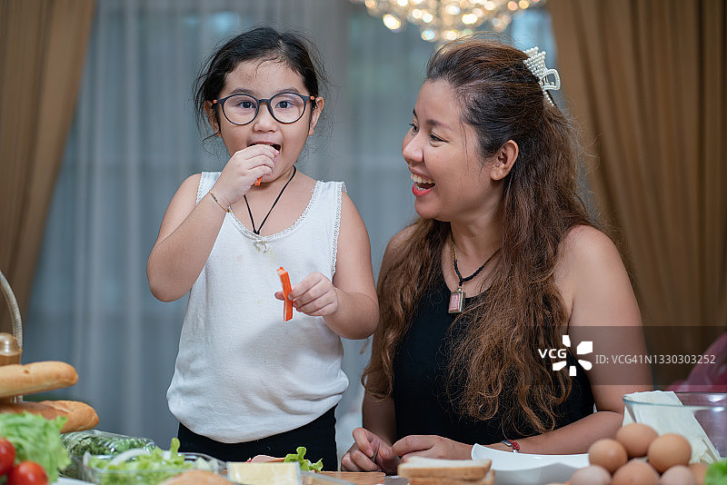 小女孩和家人一起烹饪健康的食物，开心的在家里聚会图片素材