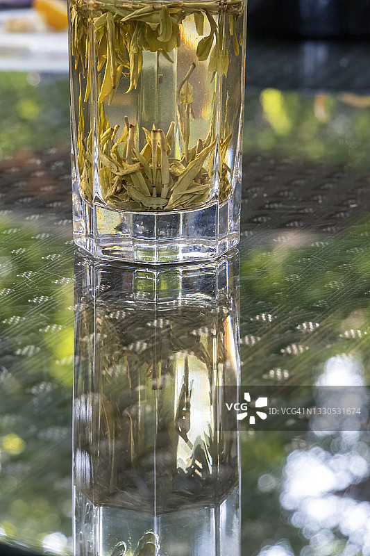 玻璃桌上放着装有绿茶的玻璃茶杯图片素材