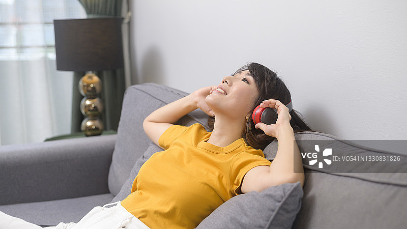 年轻快乐的女人听着音乐，在家里放松图片素材