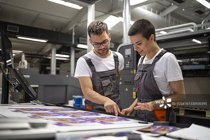 印刷机操作员在印刷厂检查图形质量和颜色值。图片素材