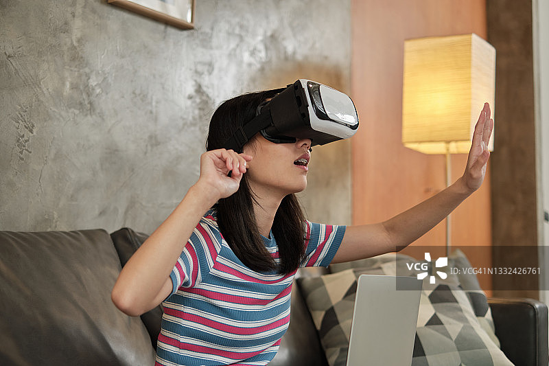 亚洲女性戴着虚拟现实头盔，观看3D虚拟模拟。图片素材