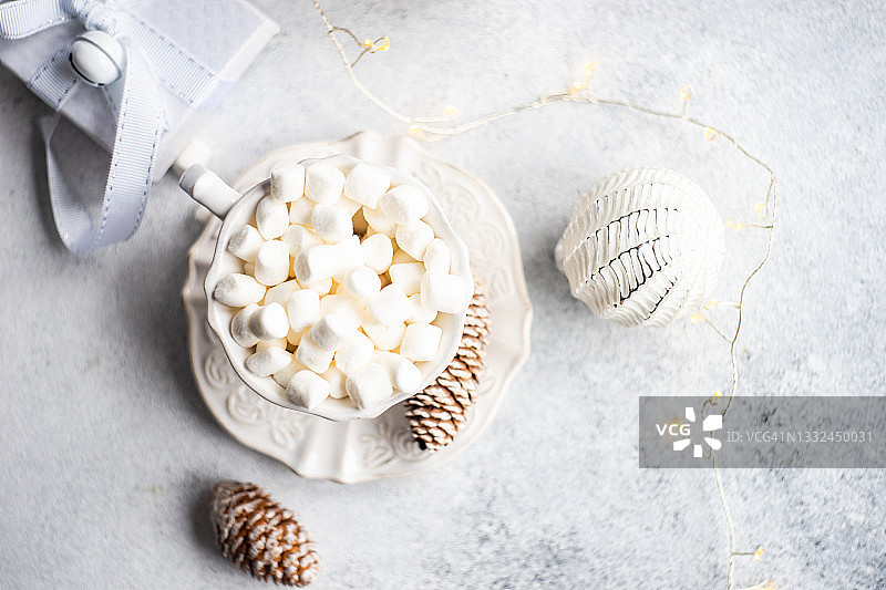 俯瞰一杯微型棉花糖旁边的圣诞礼物，装饰品和串灯图片素材