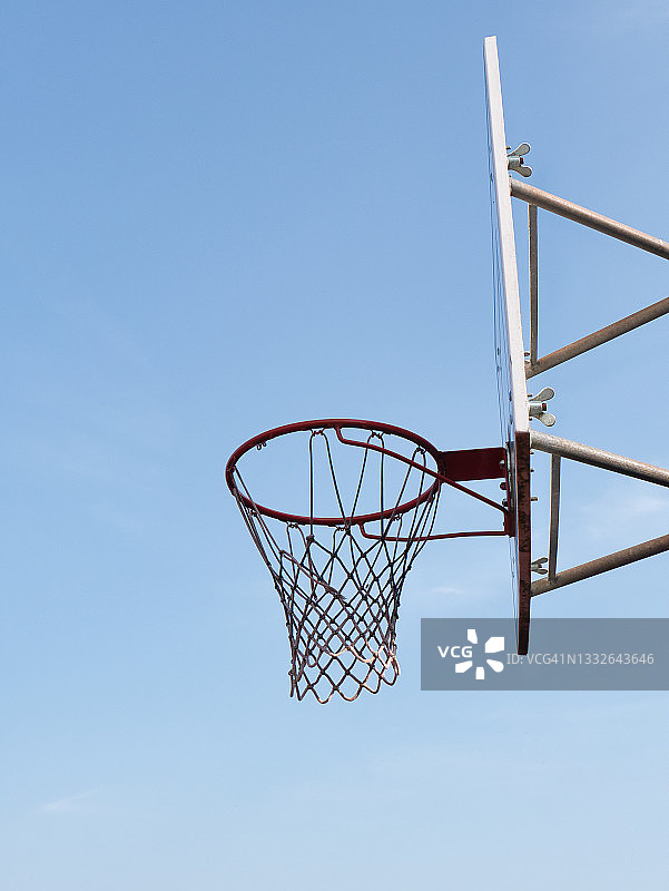 篮球场上带篮板的篮筐的侧视图，在蓝天的衬托下图片素材