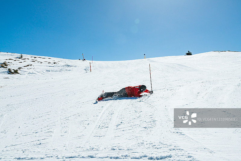 年轻的滑雪者摔倒在速降滑雪-真实的事件图片素材