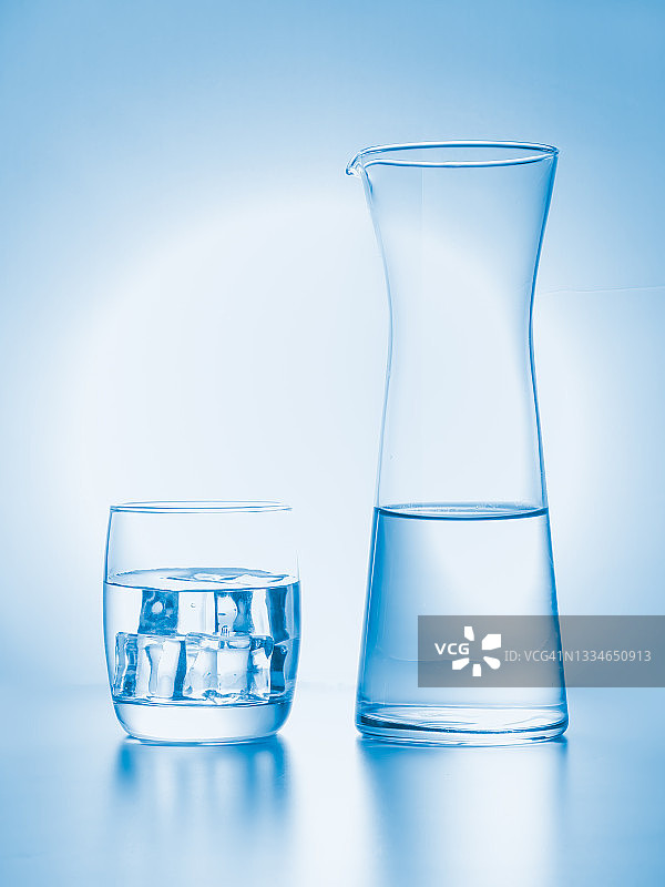 玻璃与冰和水壶的饮用水在天蓝色的背景图片素材