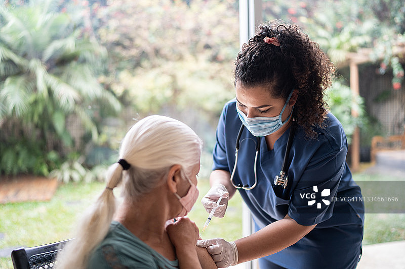 护士佩戴防护口罩为老年妇女接种疫苗图片素材