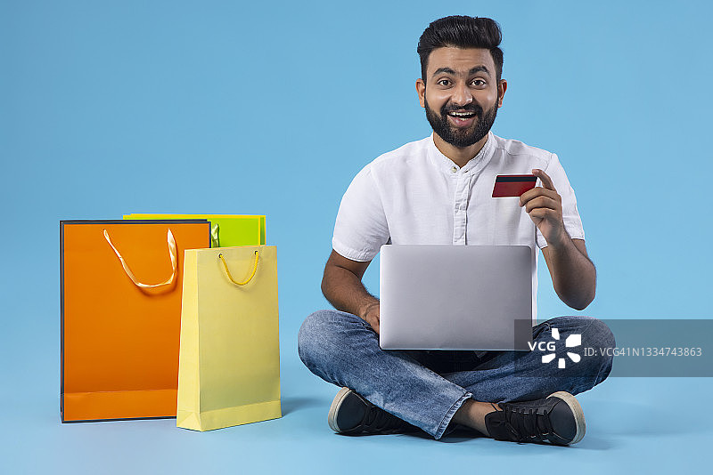 一个大胡子的年轻人正开心地用借记卡在网上购物图片素材