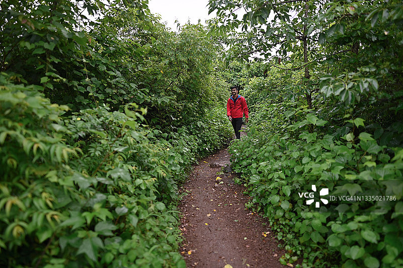 一个年轻人走在森林的狭窄小道上图片素材