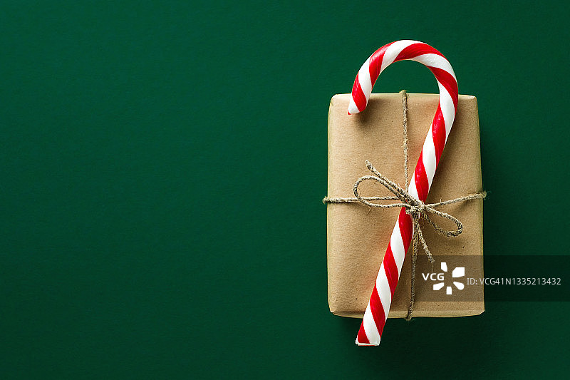 圣诞红白相间的糖果，用黄麻绳系礼物，在美丽的绿色节日背景上。庆祝快乐圣诞节的概念。图片素材