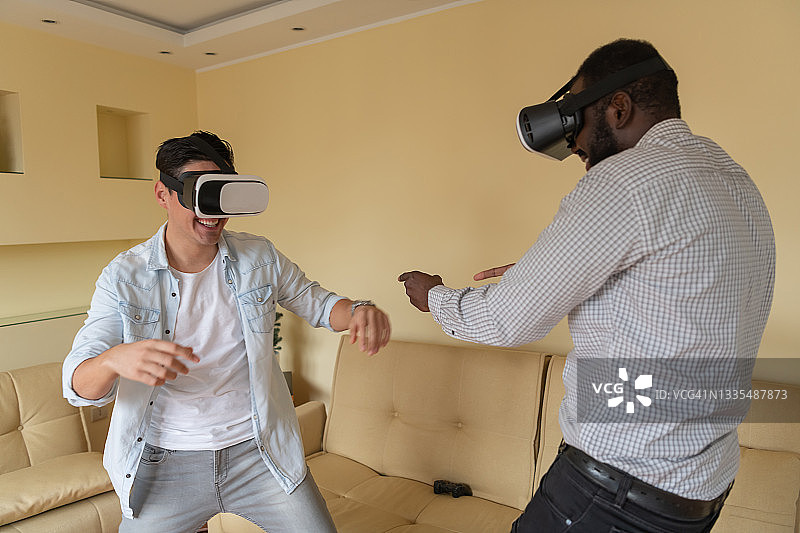 快乐的男人和他的非洲朋友正在用虚拟现实眼镜浏览虚拟世界。图片素材