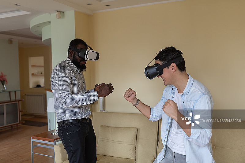 一个年轻人和他的朋友戴着虚拟现实眼镜，一边玩3D游戏一边做手势。图片素材