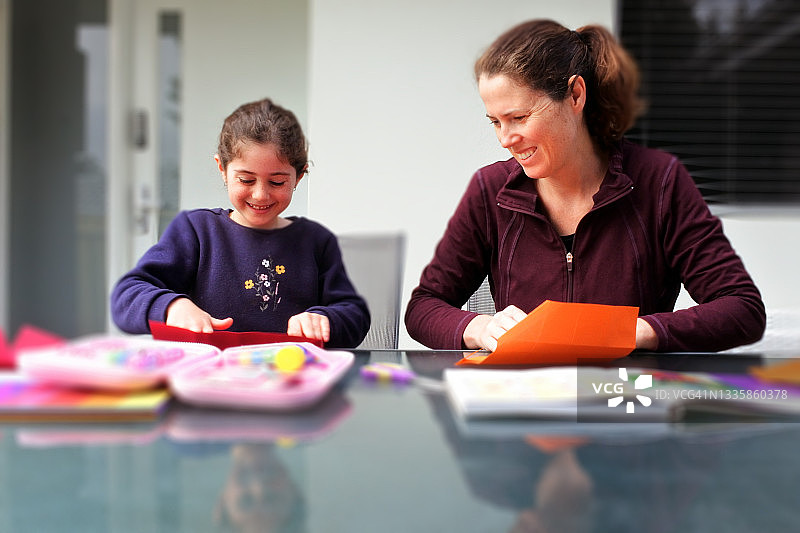 母亲和女儿一起在家里的露台上创作折纸艺术品图片素材
