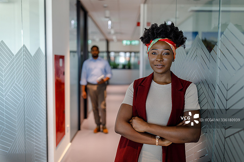 一位年轻的成功的非洲女商人在公司办公室里站着走着。图片素材