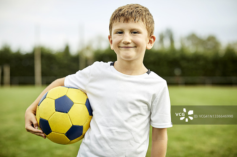 男孩在训练场上拿着足球的肖像图片素材