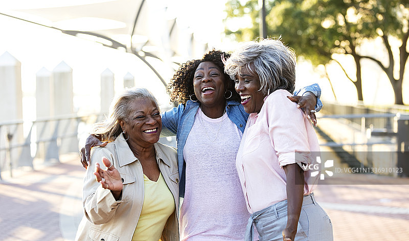 非裔美国妇女在户外笑着，拥抱着图片素材