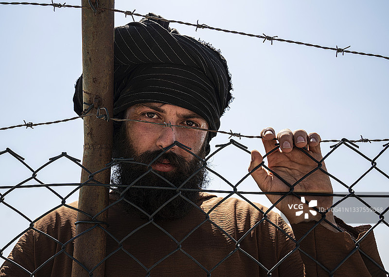 一个难民站在栅栏后面图片素材